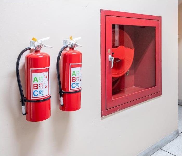 img src =”extinguisher” alt = "two fire extinguisher hanging on a tan interior wall” >